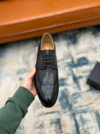 Prada unisex lace-up oxford shoe, dark leather with brogue perforations, held upright