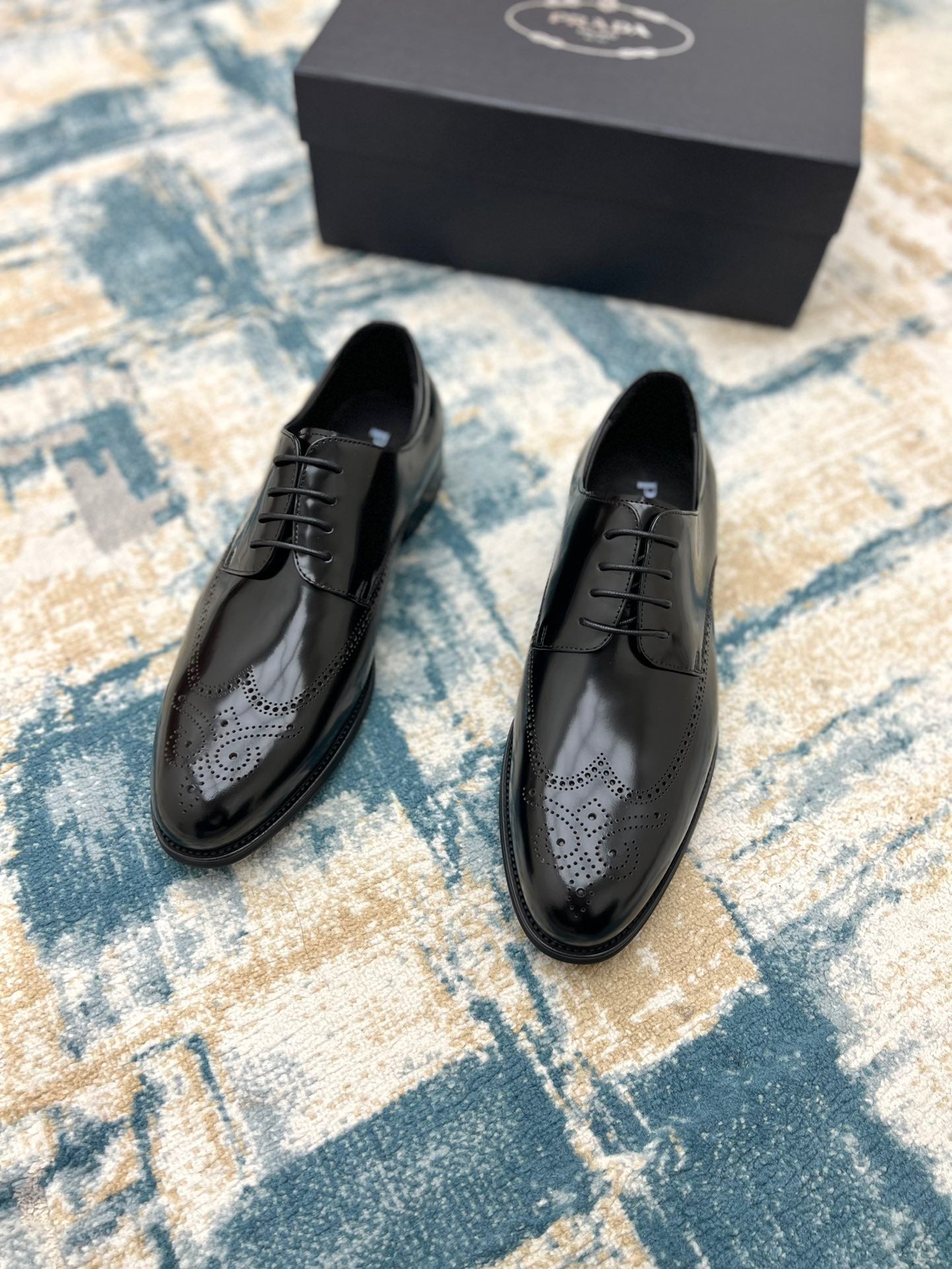 Black leather lace-up derby shoes with perforated toe, front view
