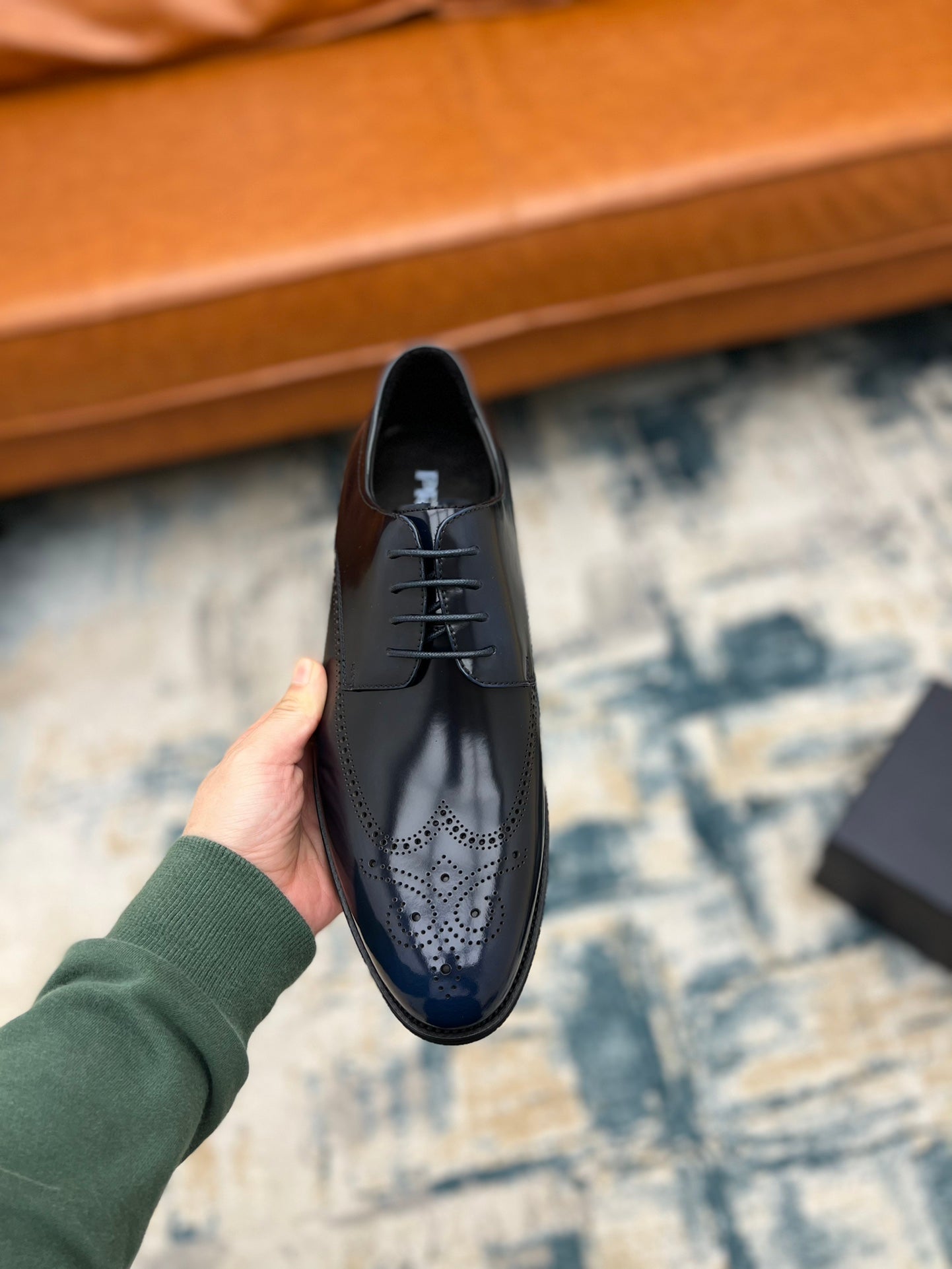Prada dark leather lace-up shoe held upright, front laces and perforated toe detail