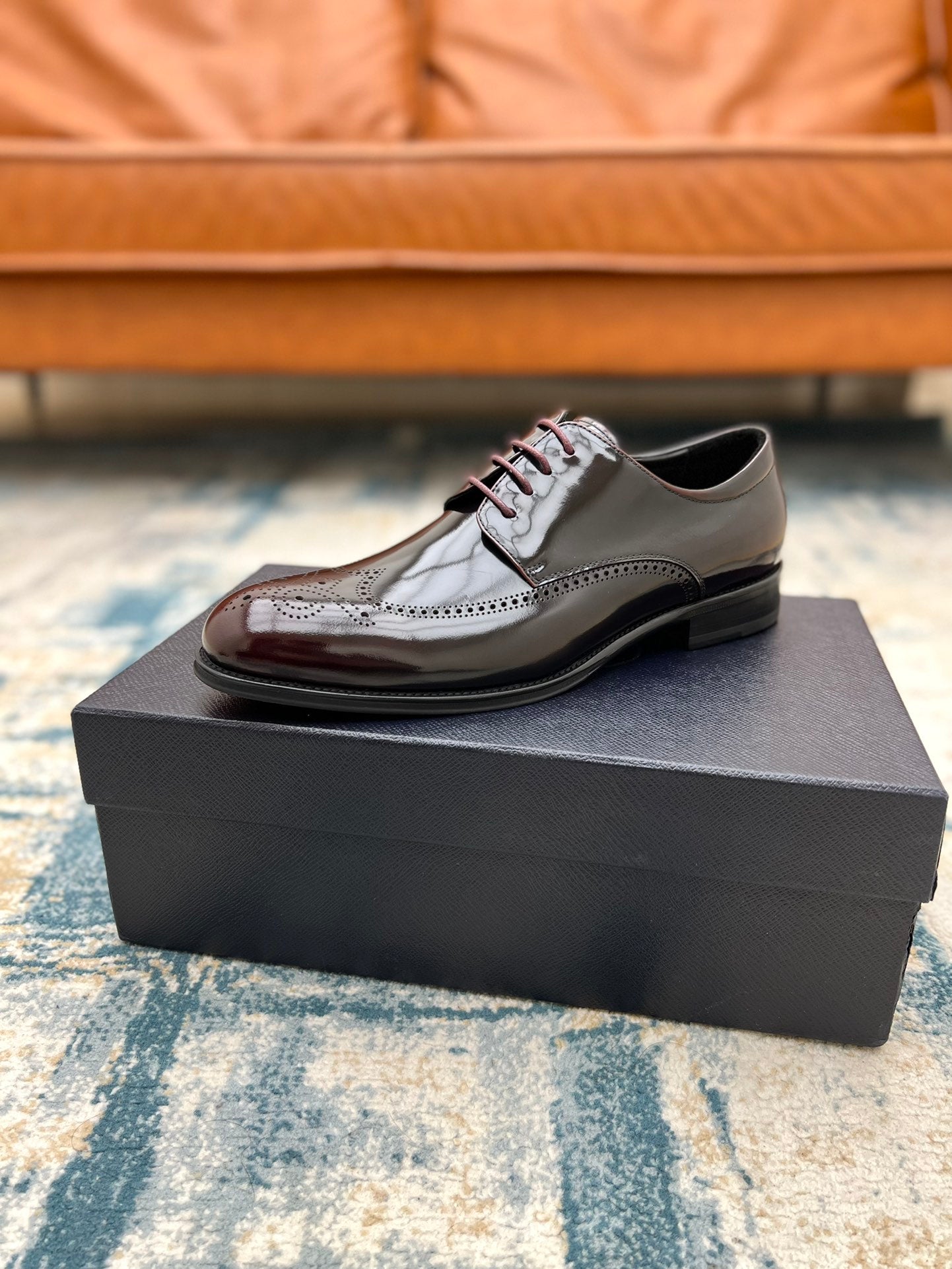 Prada unisex leather lace-up shoe with brogue detailing, side view on black box