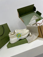 White Gucci unisex sneakers with blue-yellow star logos on side, front view