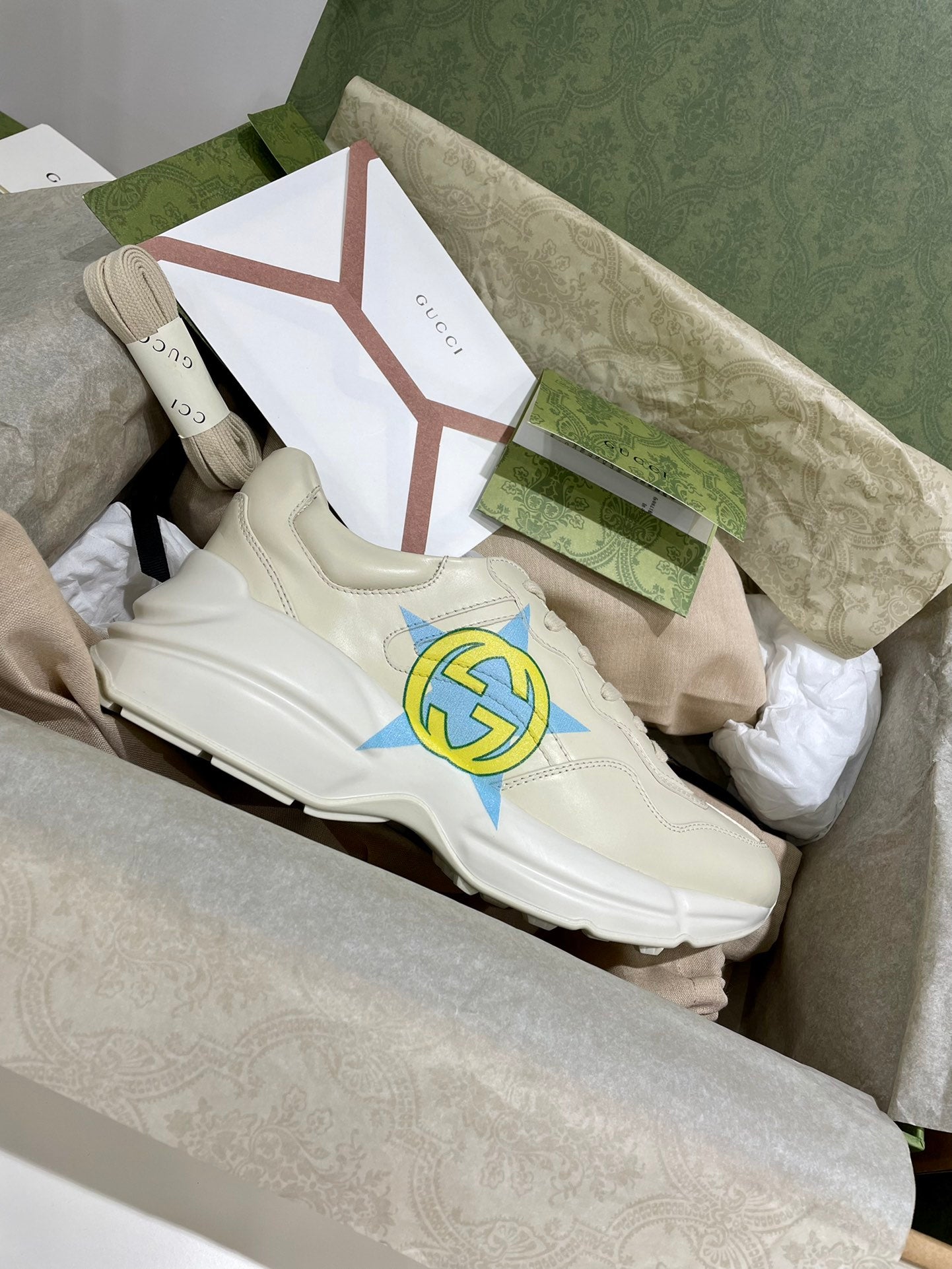 White Gucci unisex sneakers, side and lace details with blue-yellow star logo