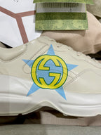 White Gucci unisex sneaker close-up with blue and yellow star logo on side