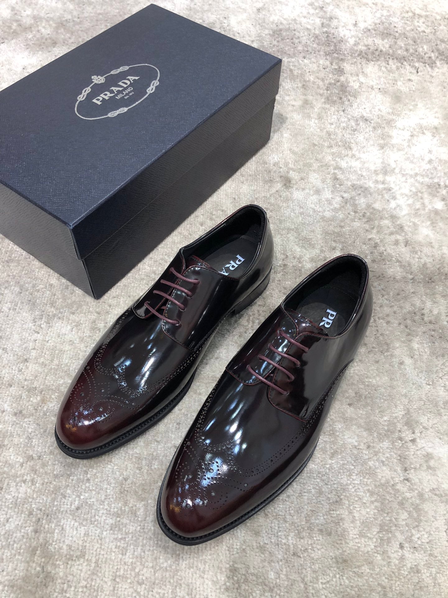 Prada lace-up dress shoes in dark brown glossy leather, angled front pair