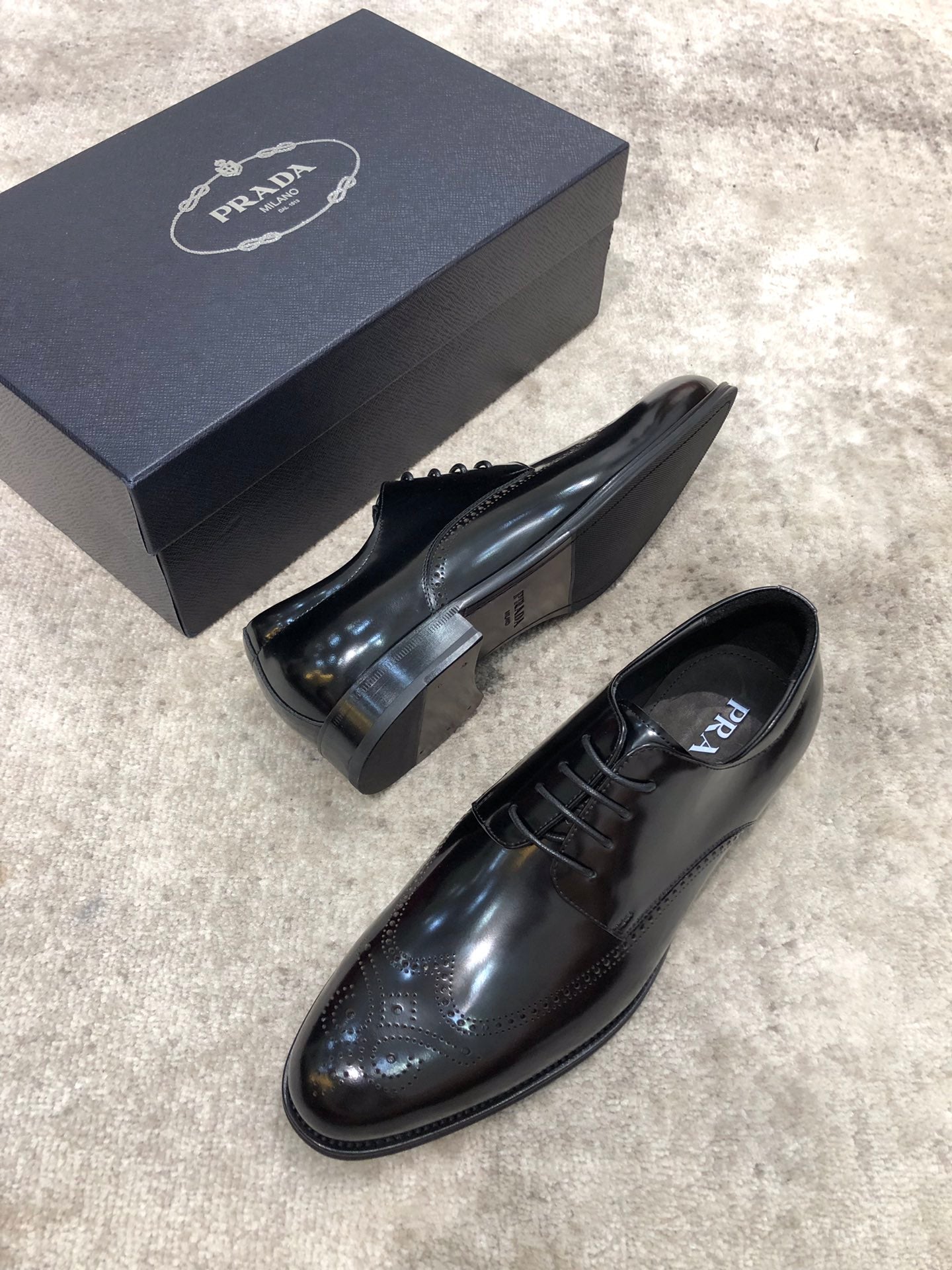 Prada lace-up dress shoes in glossy dark leather, side view, with box