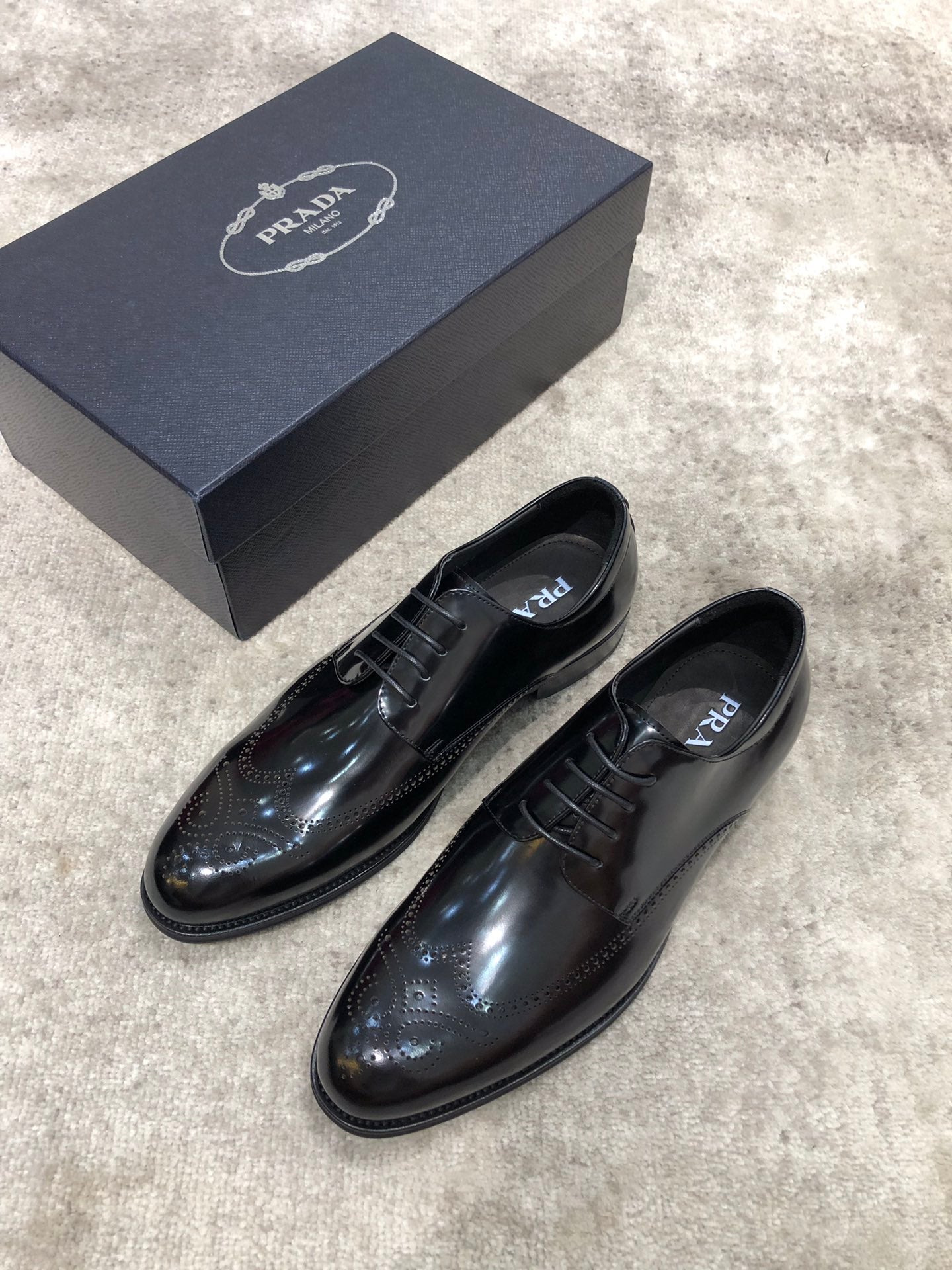 Prada lace-up dress shoes in dark patent leather, brogue-style detailing, with box