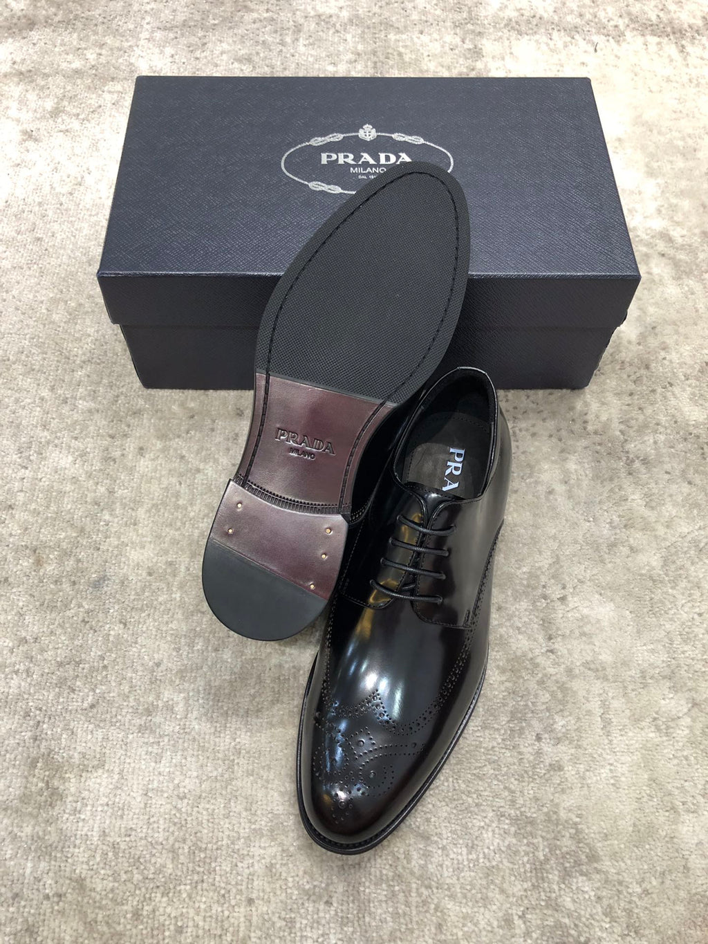 Prada lace-up shoes with dark leather and printed lining, one shoe shown with box