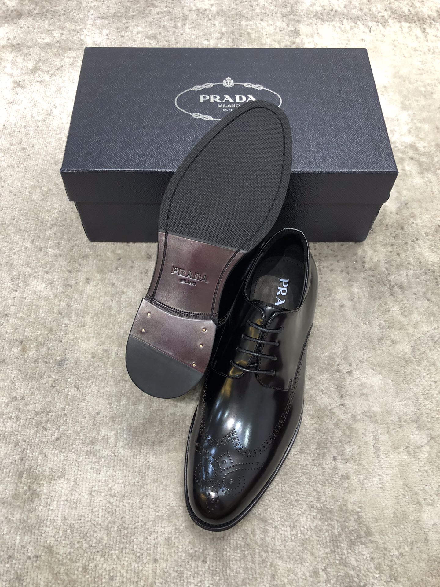 Prada lace-up shoes with dark leather and printed lining, one shoe shown with box
