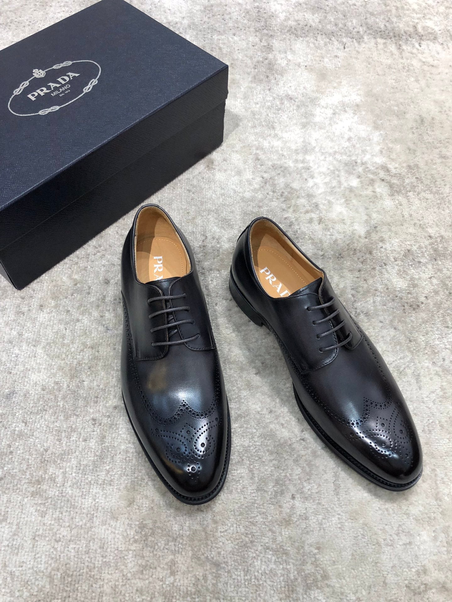 Prada black leather lace-up oxford shoes with brogue detailing, side angle view.