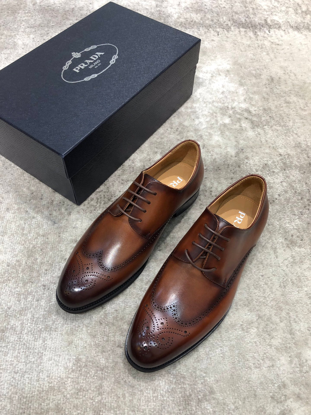 Prada brown leather lace-up brogue shoes, angled view with wingtip perforations