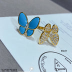 Gold-tone butterfly earrings with blue enamel petals and clear stone pavé on card
