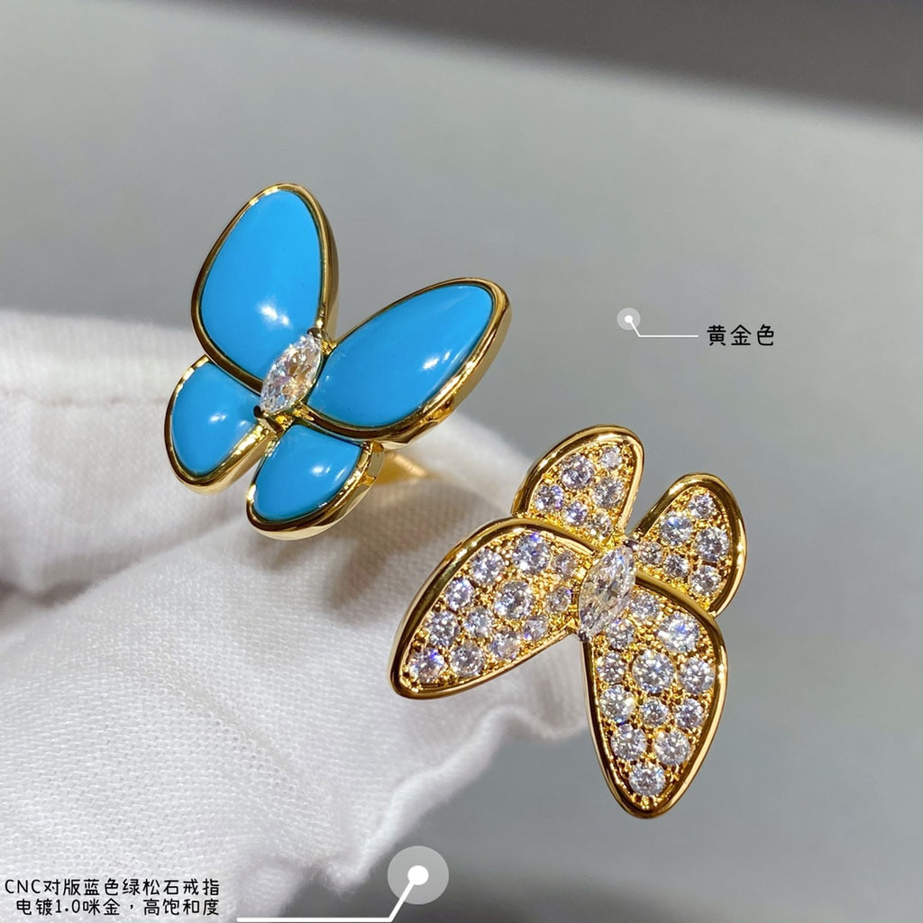 Gold-tone butterfly earrings on white fabric with blue enamel petals and clear stones