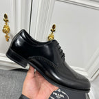 Prada unisex lace-up dress shoe, black leather with perforated trim and low heel.