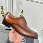 Prada unisex lace-up oxford shoe held up, dark brown leather with brogue trim and black sole