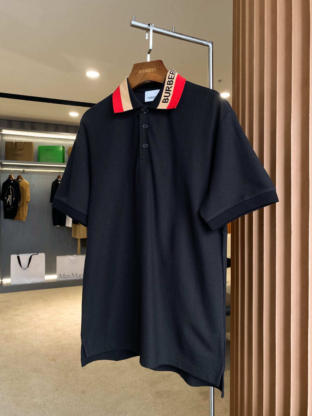 Black Burberry polo shirt on hanger, red-and-beige striped collar