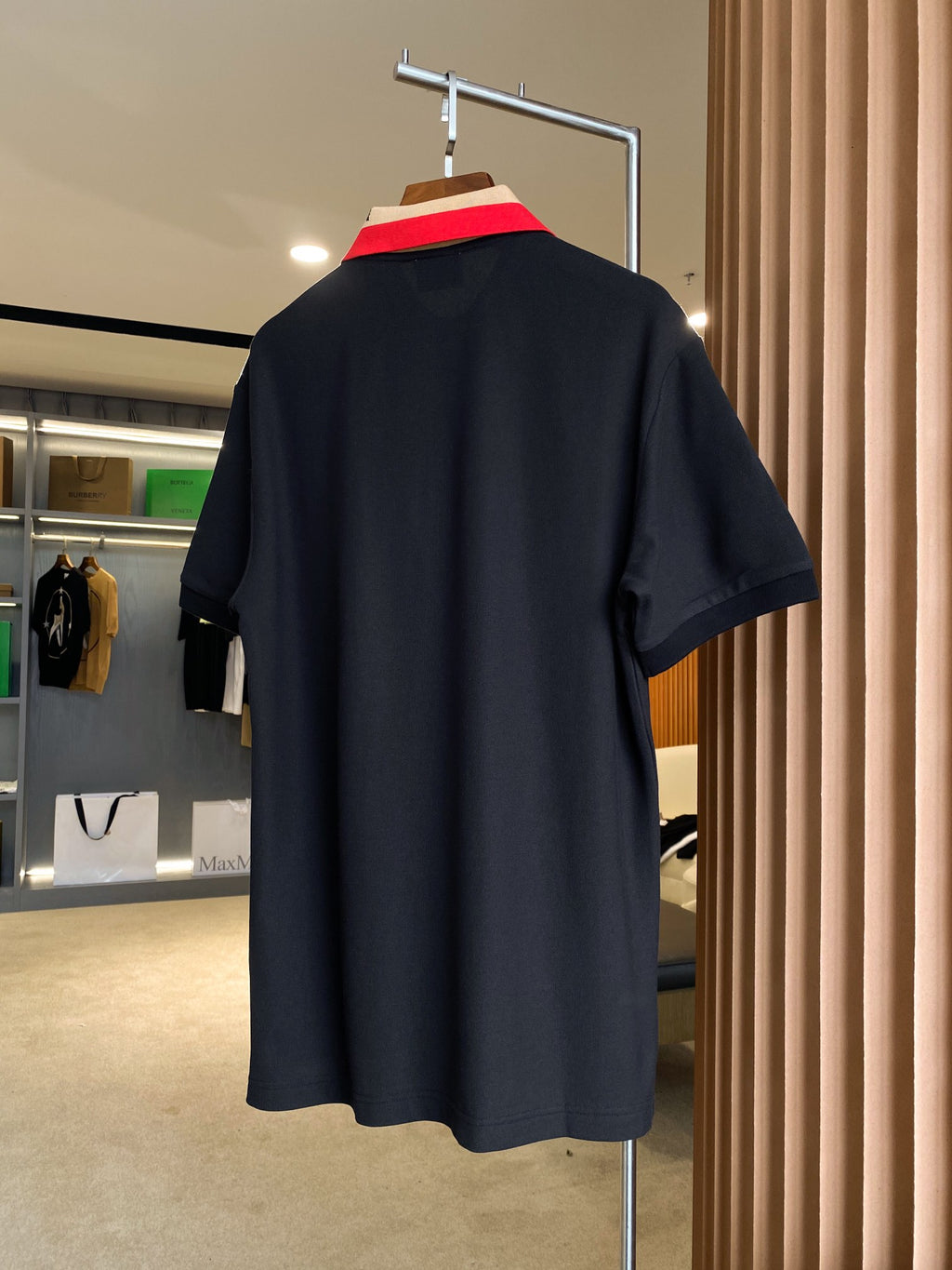 Back view of black Burberry polo shirt on hanger