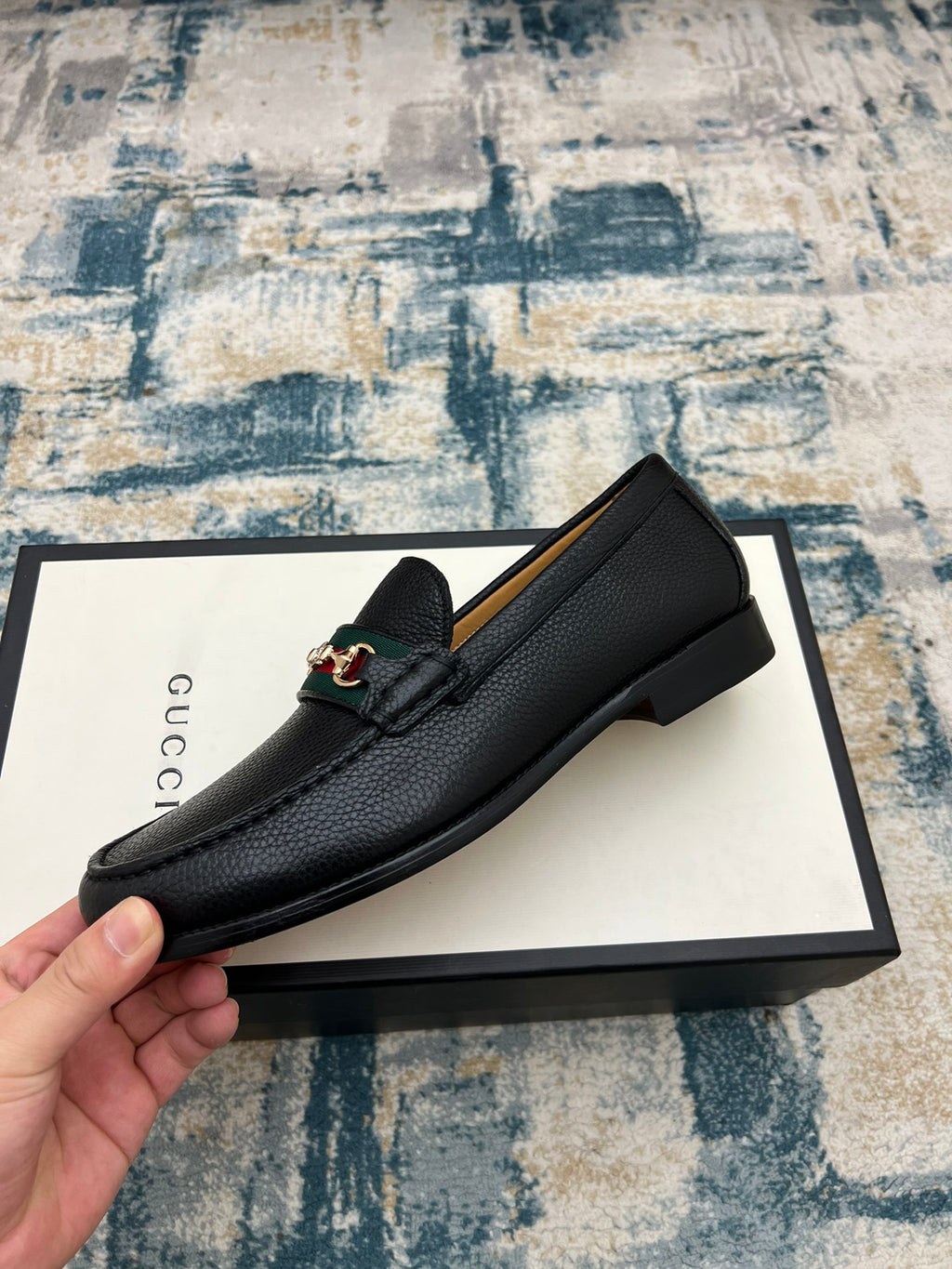 Black leather Gucci unisex loafer with horsebit detail, side view on box