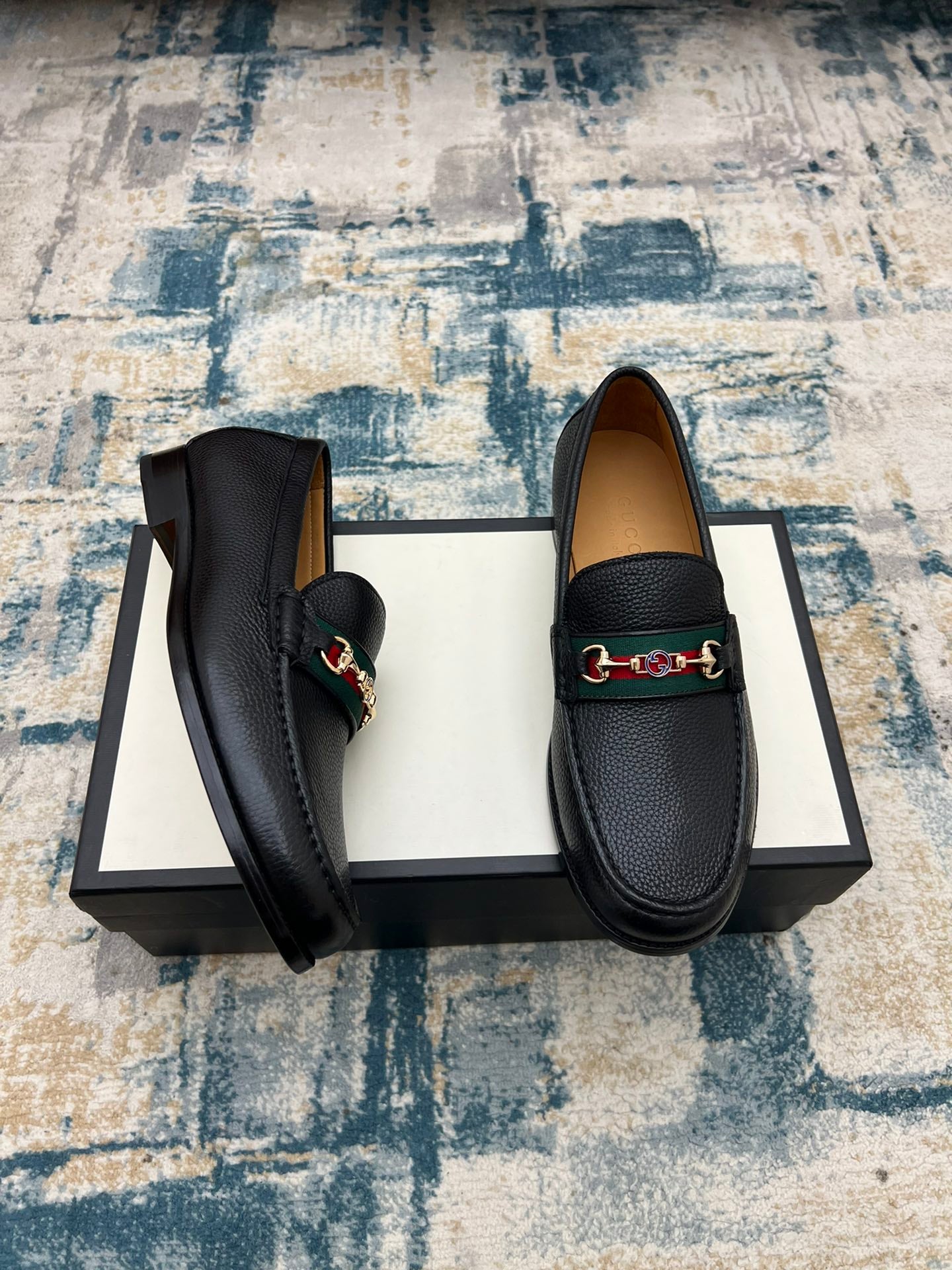 Black leather Gucci unisex loafers shown from side angle, horsebit detail