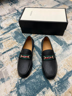 Black leather Gucci unisex loafers with horsebit detail, pair on floor by box