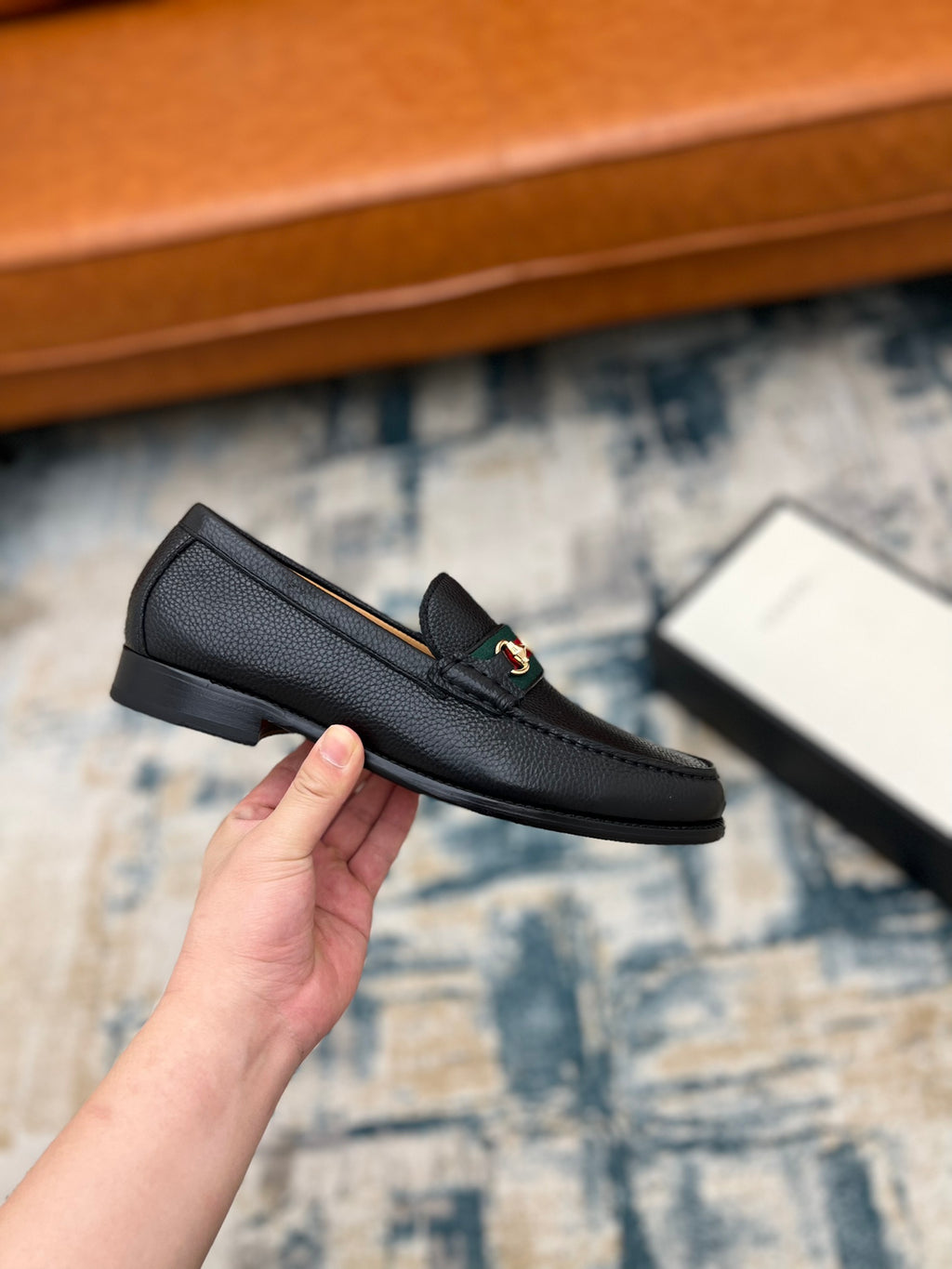 Black leather Gucci unisex loafer with horsebit detail, side profile in hand