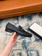 Black leather Gucci unisex loafer with horsebit detail, side profile in hand
