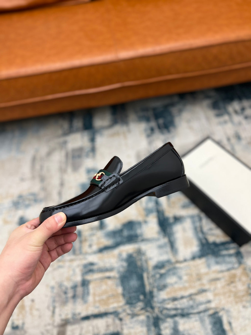 Black Gucci unisex loafer with horsebit detail, low profile side view held in hand