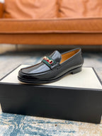 Black Gucci unisex loafer with horsebit strap detail, resting on the box in a profile view