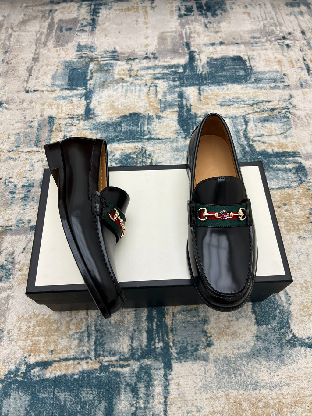 Black Gucci unisex loafers with horsebit strap detail and rounded toe, shown at an angle