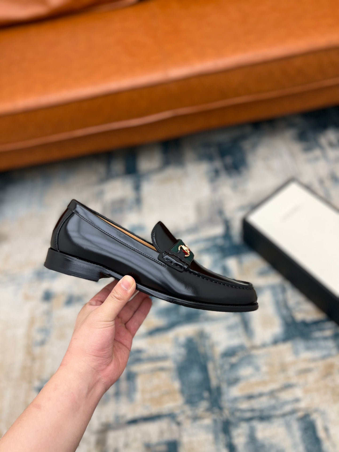 Black Gucci unisex loafer with horsebit detail, side view held in hand