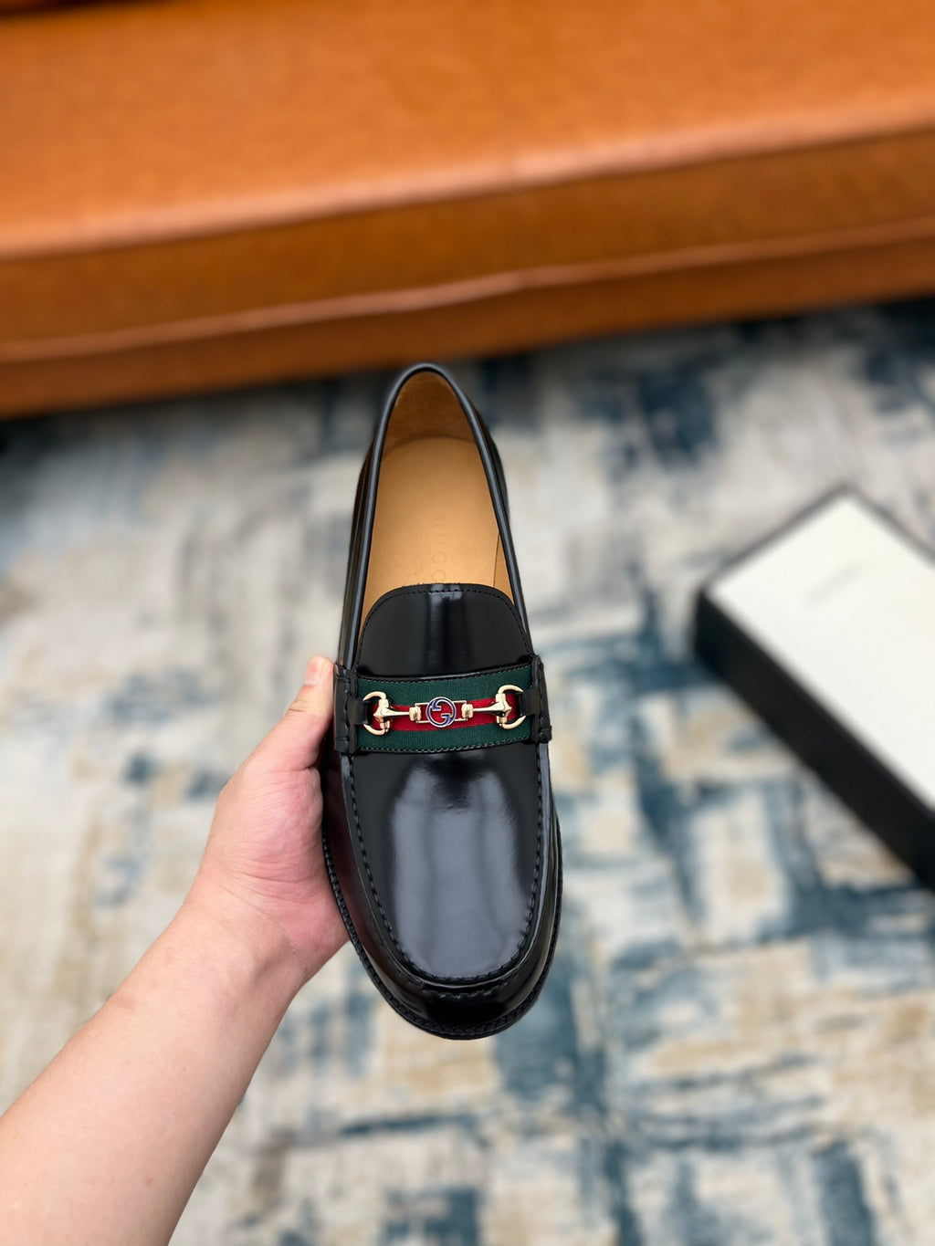 Black Gucci unisex loafer with horsebit strap detail, front view held close