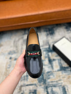Black Gucci unisex loafer with horsebit strap detail, front view held close