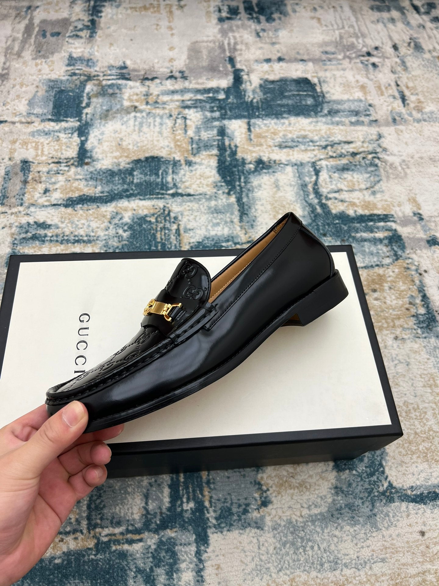 Black Gucci loafer with gold buckle on GG-printed leather, side view