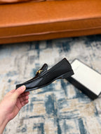 Black Gucci loafer with gold-tone buckle and low heel, side angle
