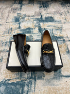 Black Gucci loafers with gold-tone buckle and textured GG print, side view