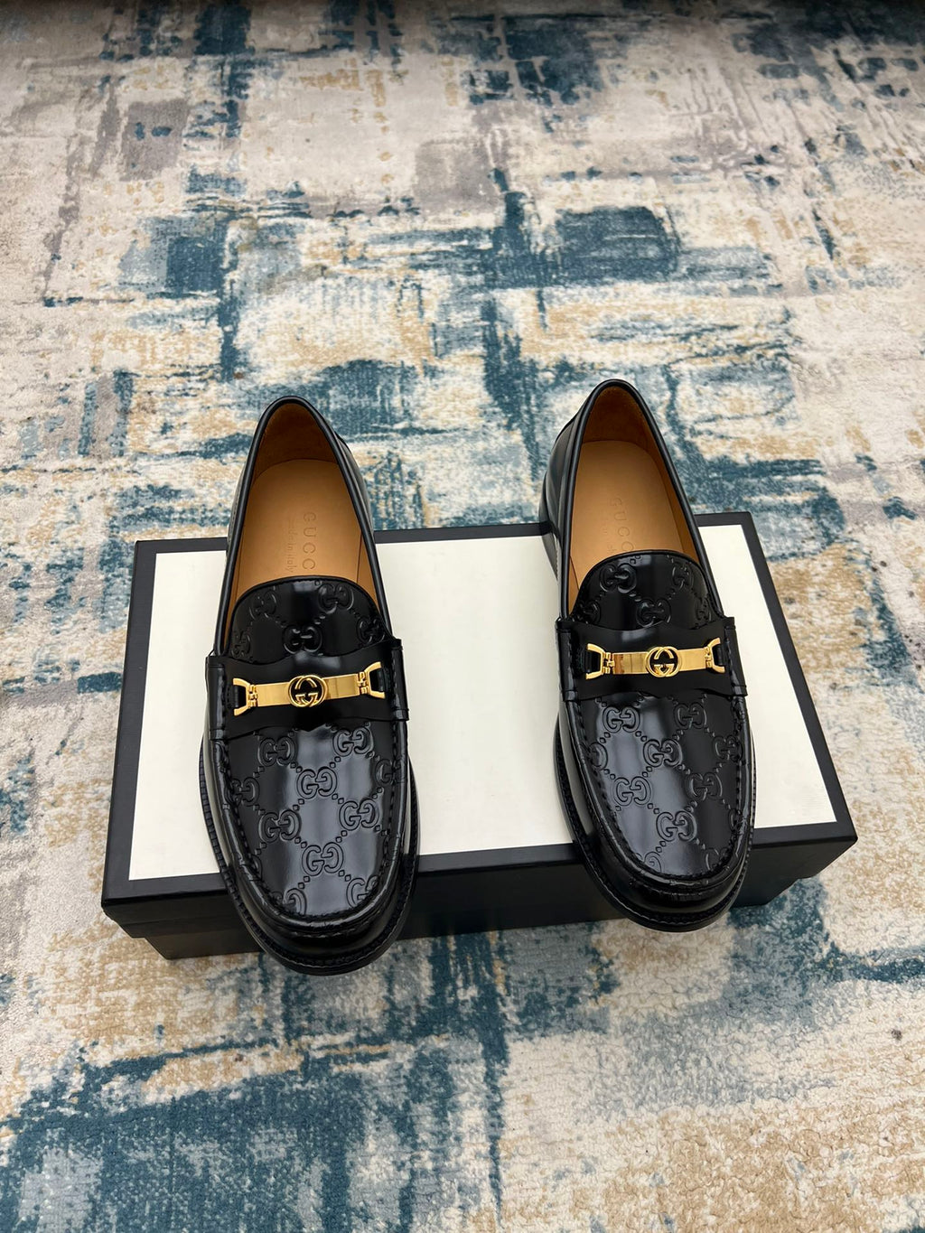 Black Gucci loafers with GG pattern upper and gold-tone buckle strap