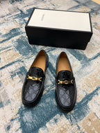Black Gucci loafers with GG pattern and gold-tone buckle, beside shoe box