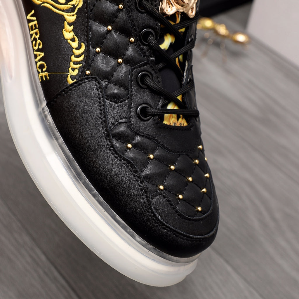 Men's Versace sneakers close-up: black quilted leather, gold stud accents, white sole.