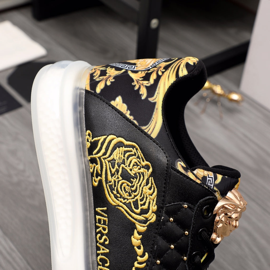 Men's Versace sneakers close-up: black leather with gold crest print and lion hardware.