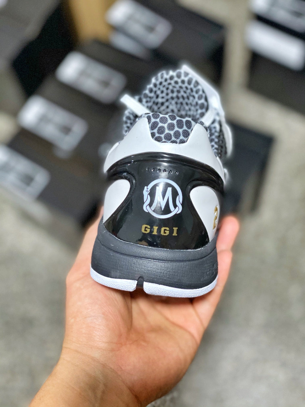 Black and white low-top sneaker heel with M logo and GIGI lettering, white sole.