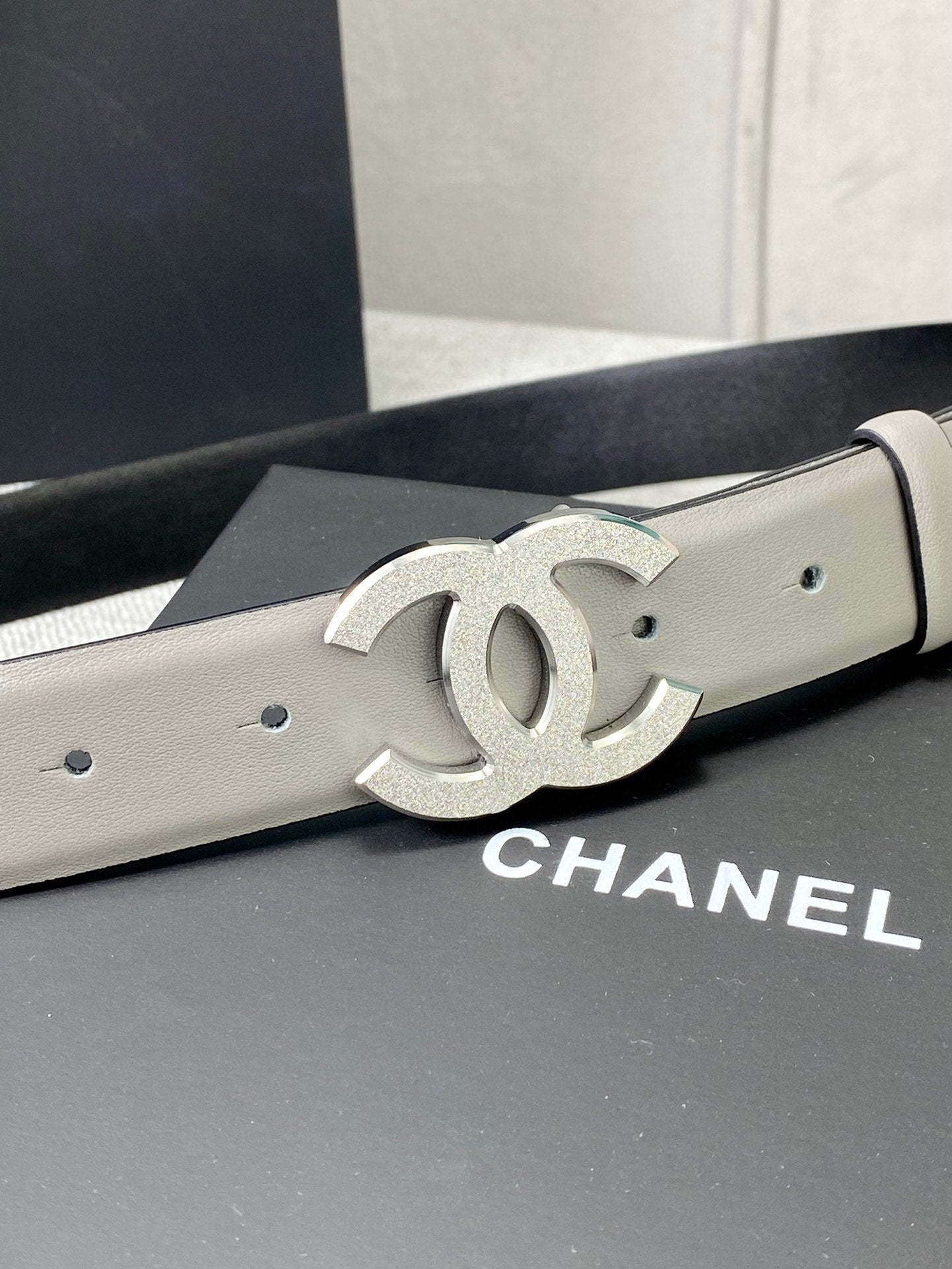 Light gray belt with silver-tone CC logo buckle detail