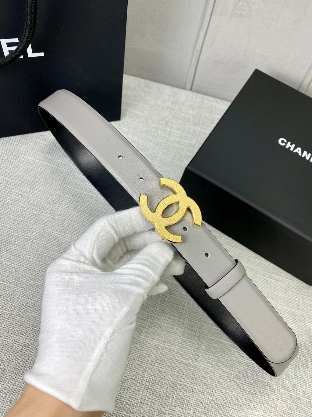 Light gray belt with gold-tone CC logo buckle detail