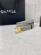 Light gray CC-buckle belt with gold logo buckle, shown near gift box