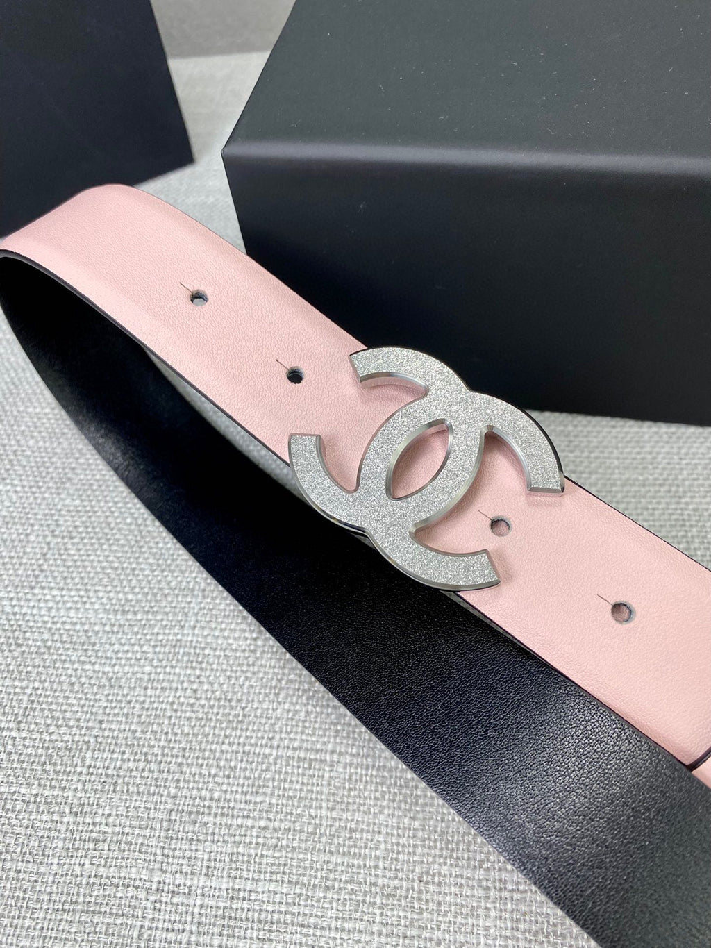 Pale pink leather belt with silver CC buckle emblem and dark backing edge.