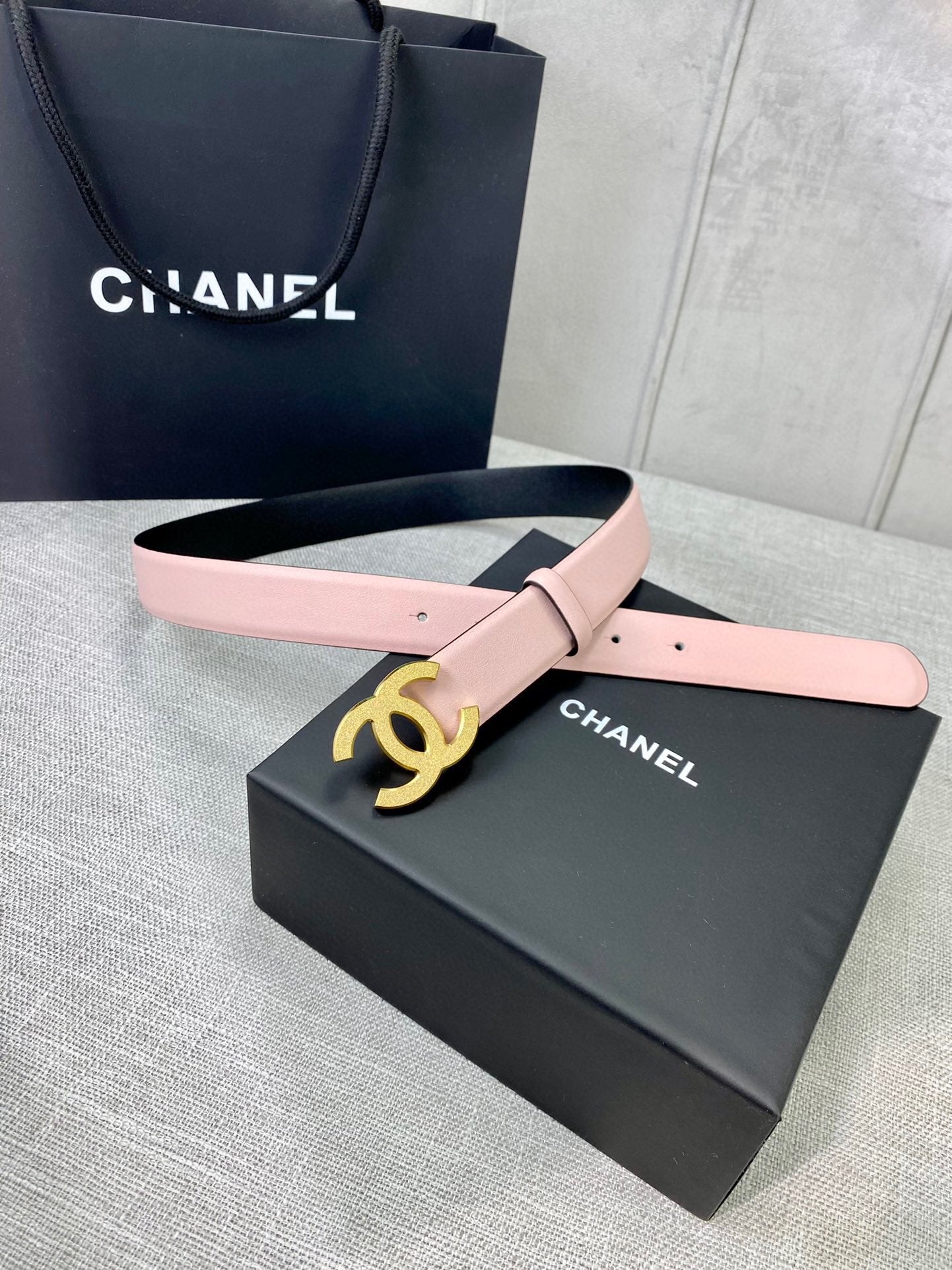 Pale pink leather belt with gold CC logo buckle and adjustable pin holes.