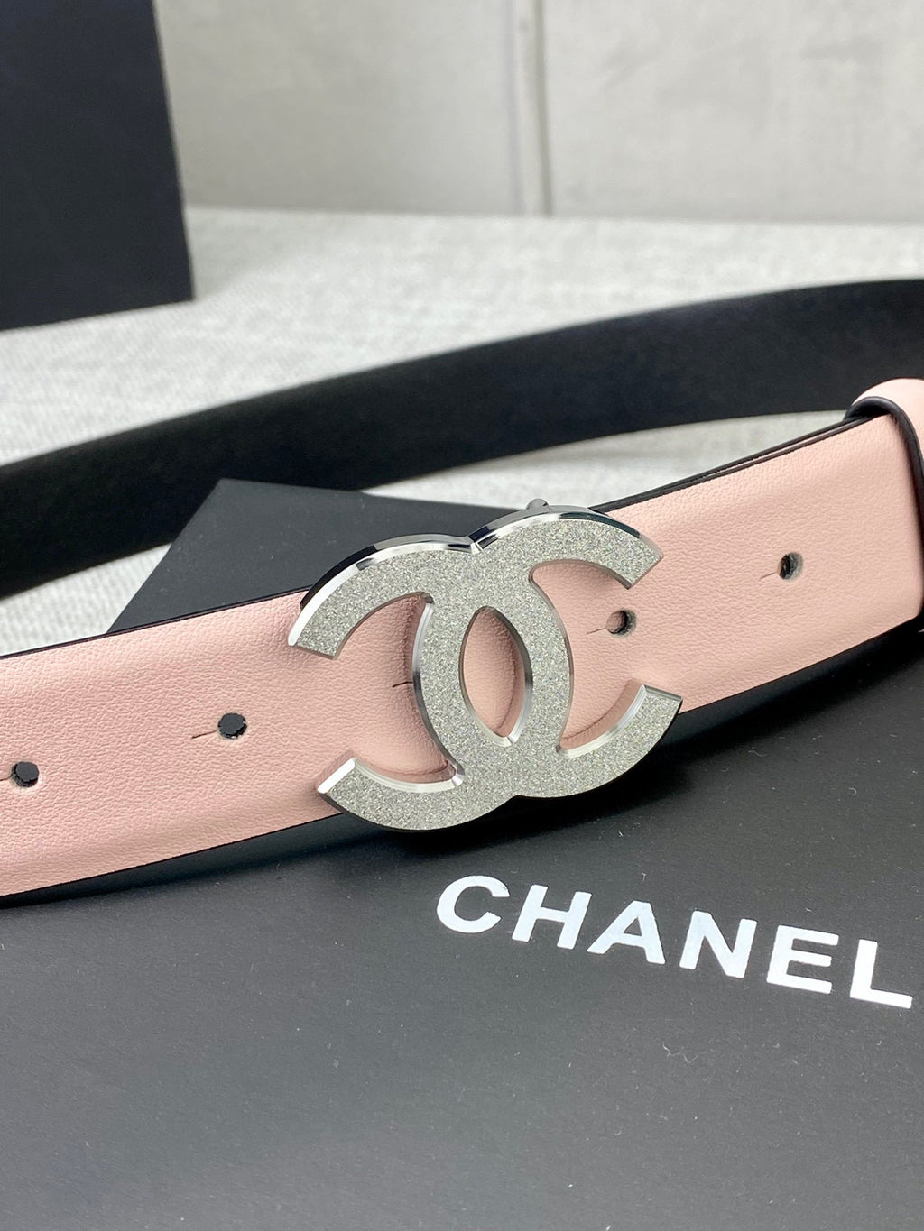 Pale pink leather belt with oversized silver CC buckle emblem on the front.