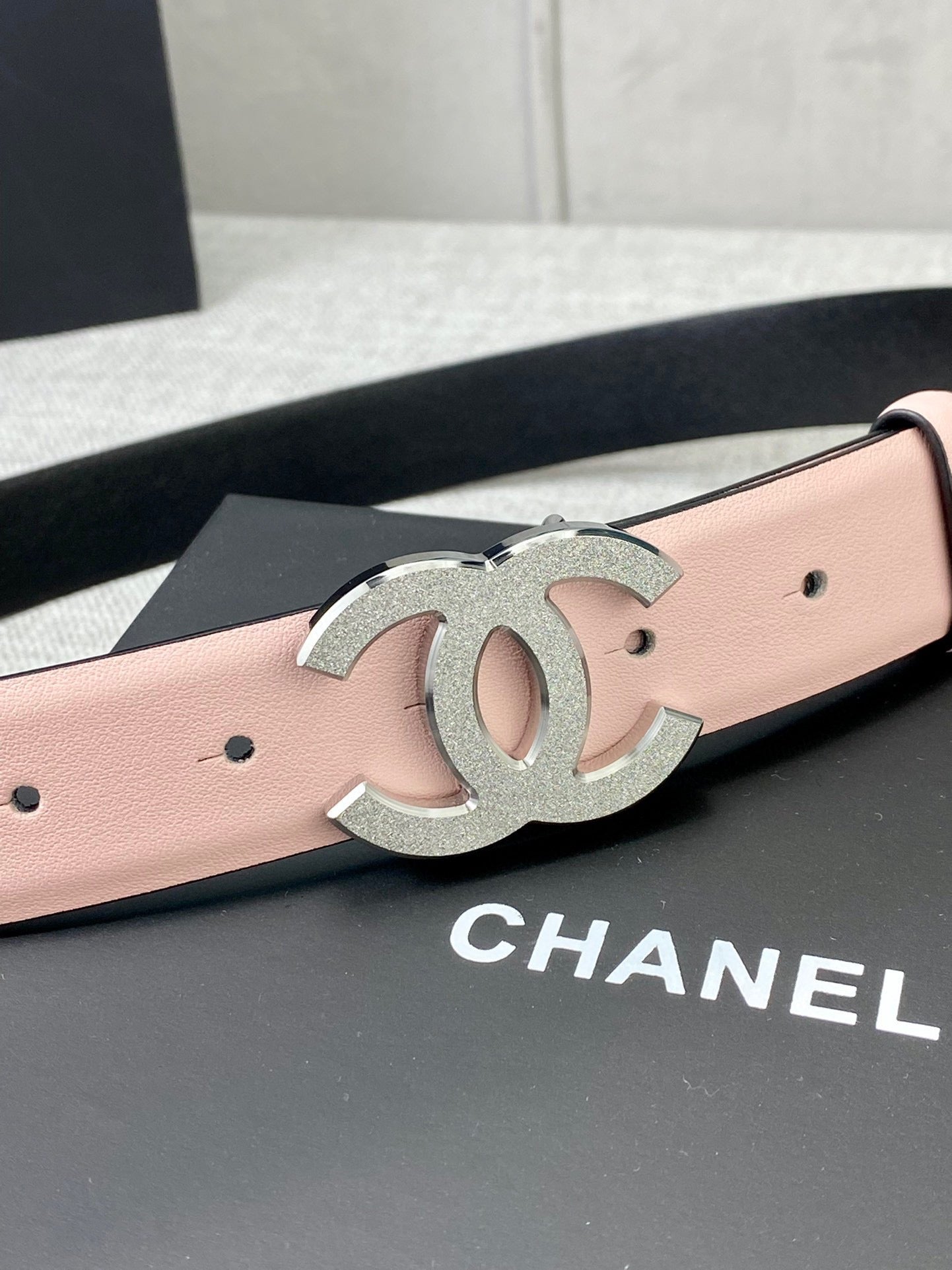 Pale pink leather belt with oversized silver CC buckle emblem on the front.