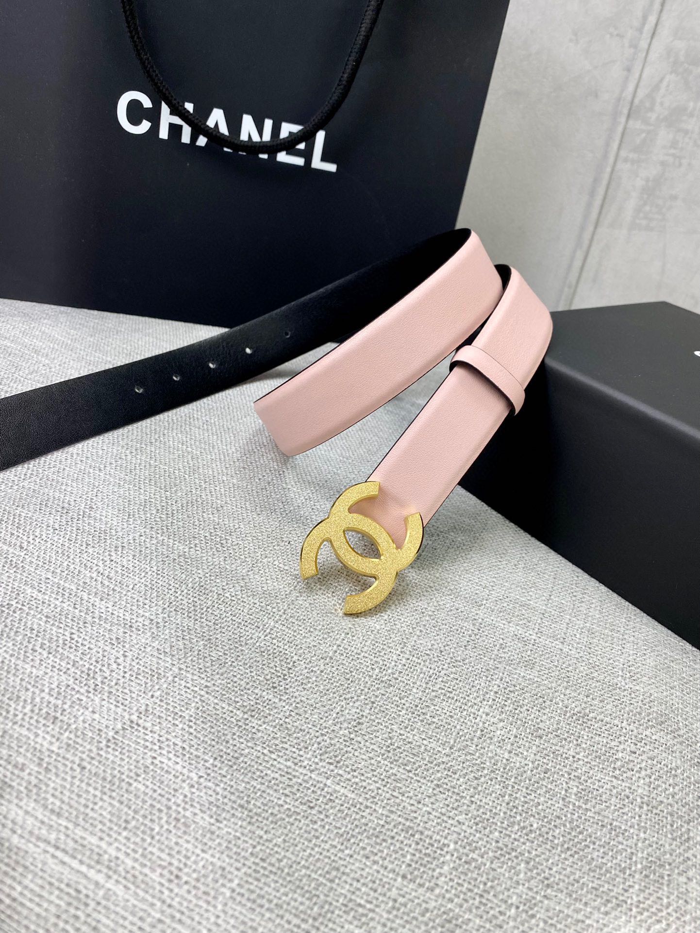 Pale pink leather belt with gold CC buckle on a wide adjustable strap.