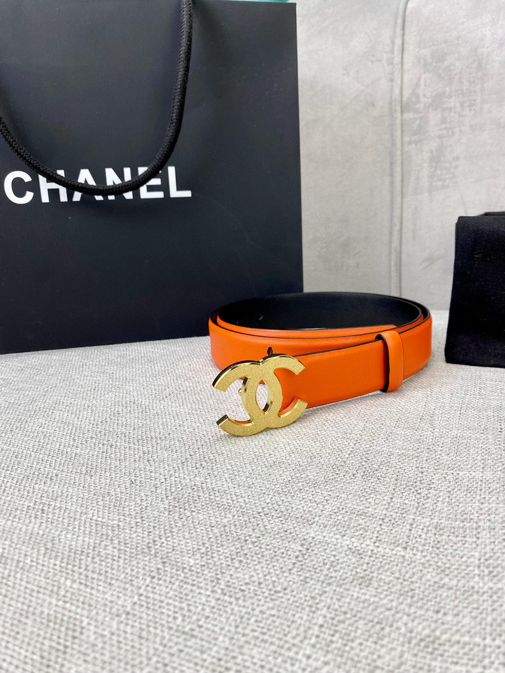 Chanel orange belt with gold CC logo buckle, angled view
