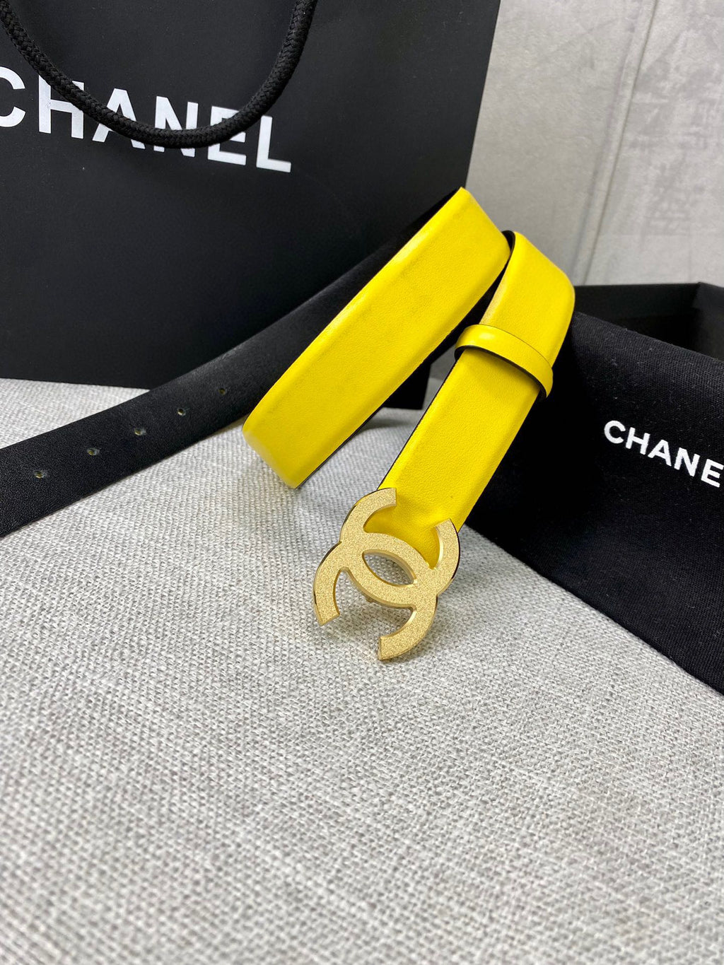 Chanel belt with bright yellow strap and gold CC buckle, coiled on display