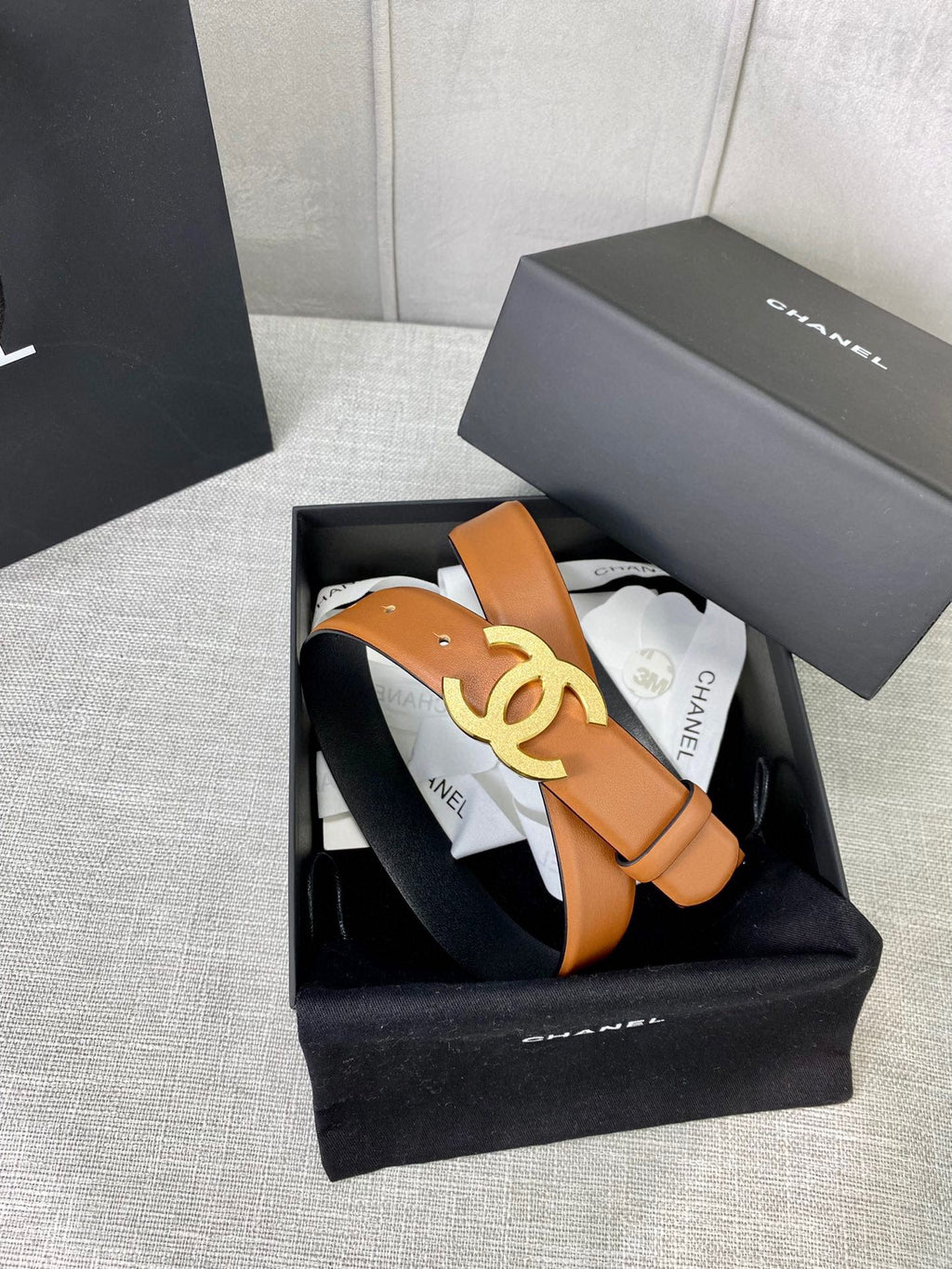 Tan leather belt with gold-tone CC buckle, in open presentation box.